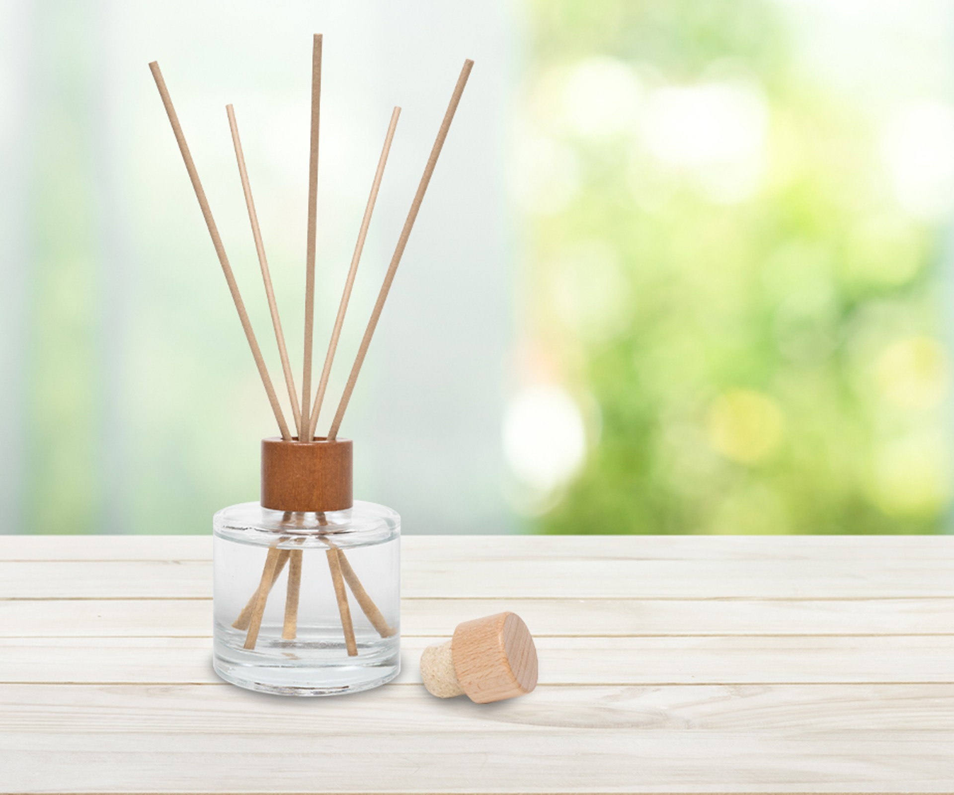 A Frosch Oase room freshener glass bottle with reed diffusers stands on a wooden table