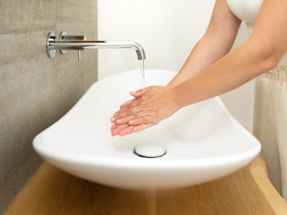 Eine Person wäscht sich an einem Waschbecken im Bad die Hände