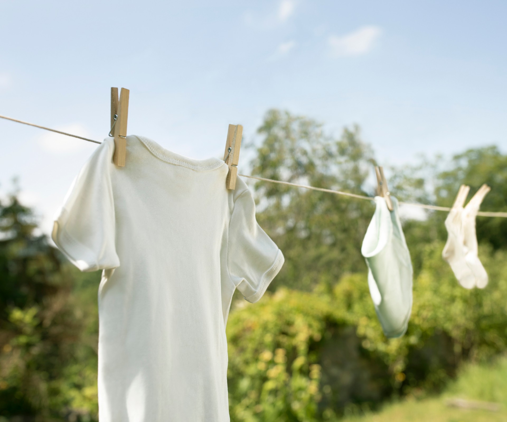 White clothes hang on a clothesline outside under blue sky