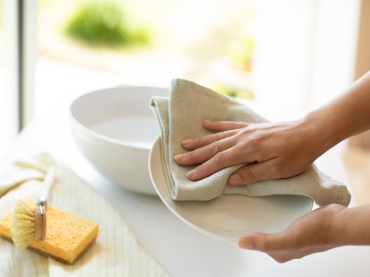 A plate is dried with a cloth in the kitchen